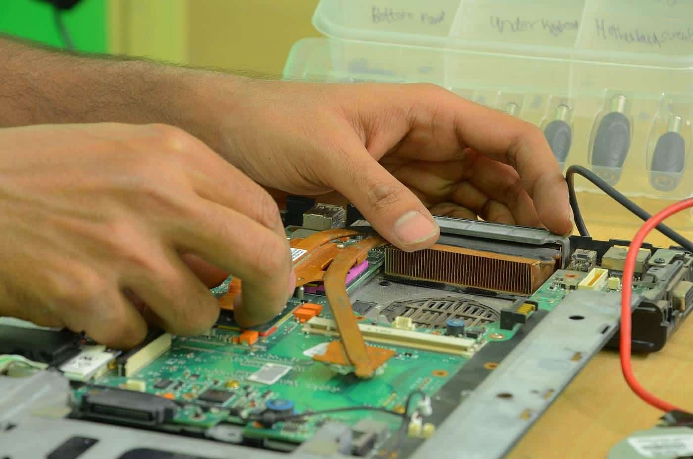 Hands working on the circuit board of an open computer