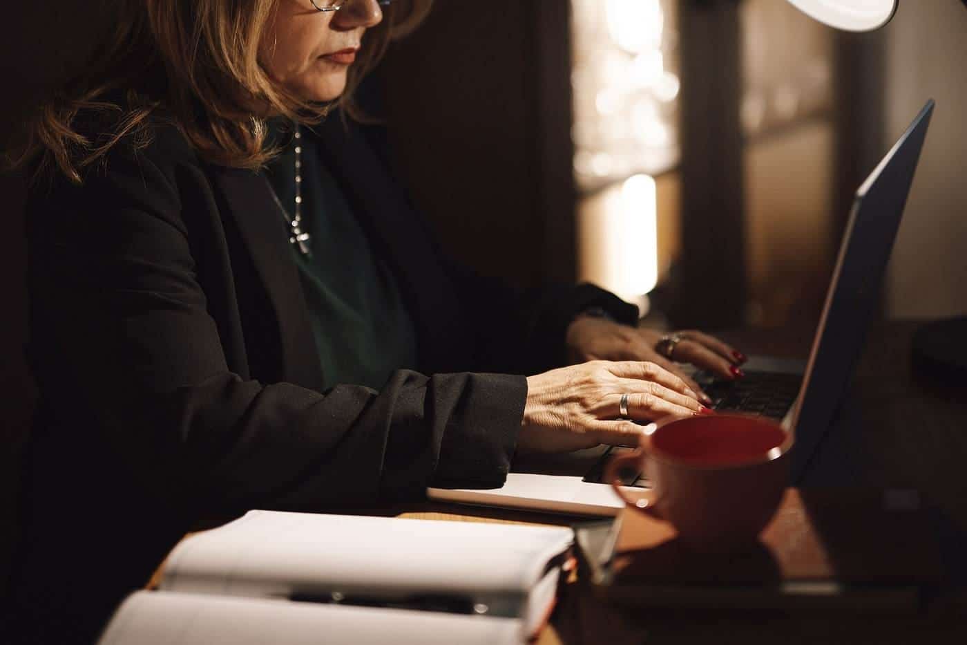A woman typing on a laptop at a desk at home