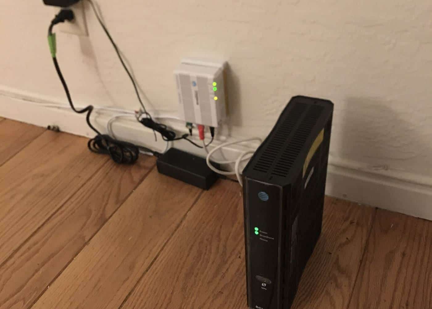A home Wi-Fi router and modem on the floor beside a wall socket